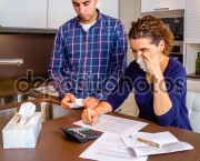 Unemployed husband reviewing the bills and wife crying by debts