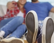 moving, home, repair and people concept - close up of couple legs relaxing and sitting on sofa with